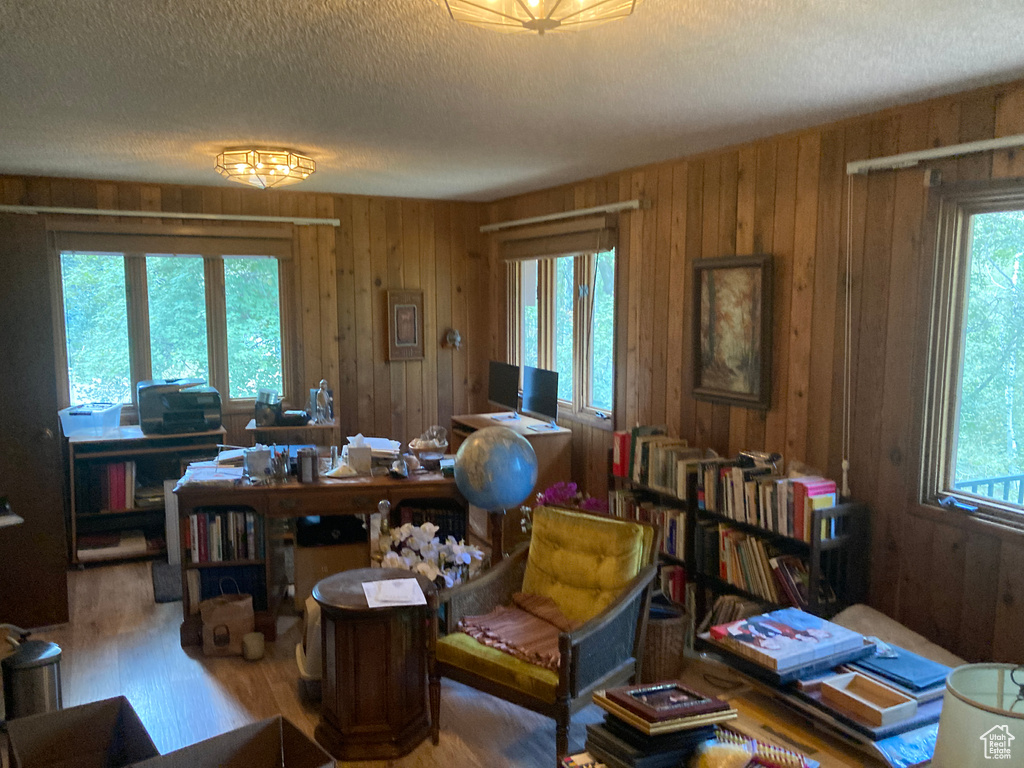 Office with a textured ceiling, wood-type flooring, and wood walls