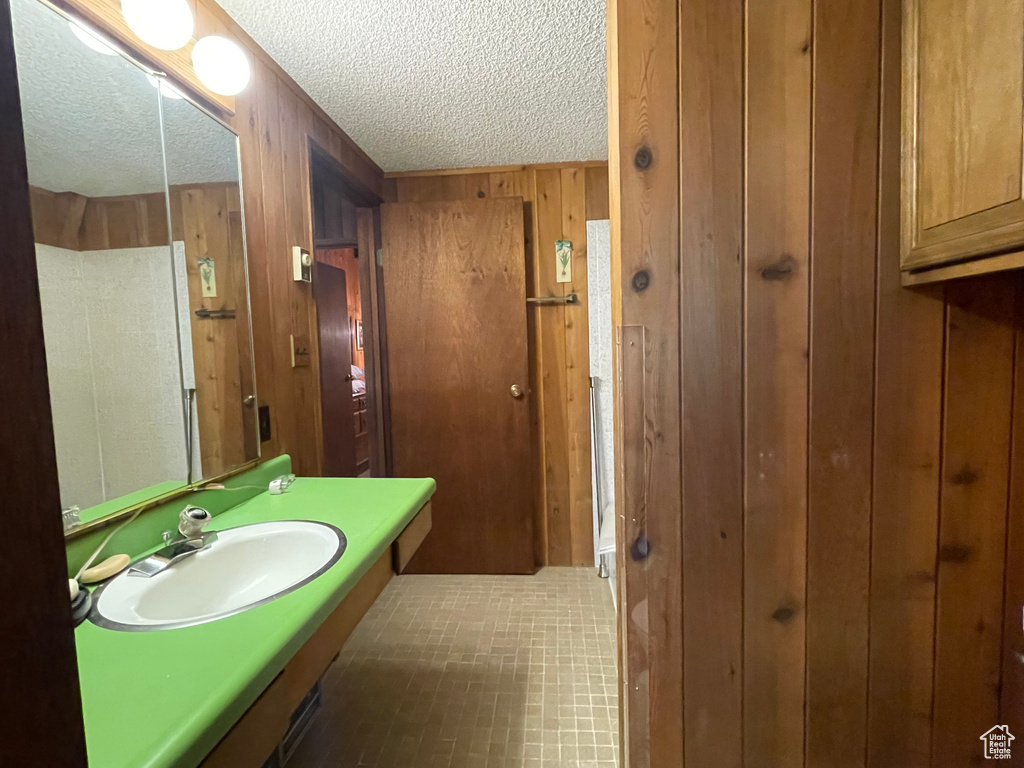 Bathroom featuring wood walls, vanity, a textured ceiling, and tile patterned floors