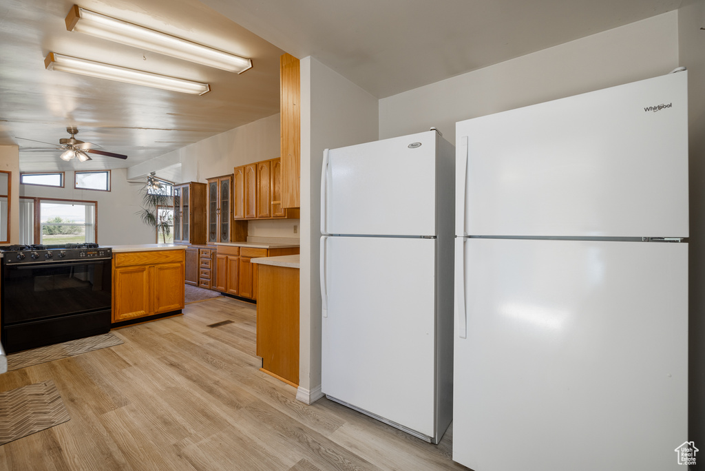 Kitchen with black range, ceiling fan, white refrigerator, and light wood-type flooring