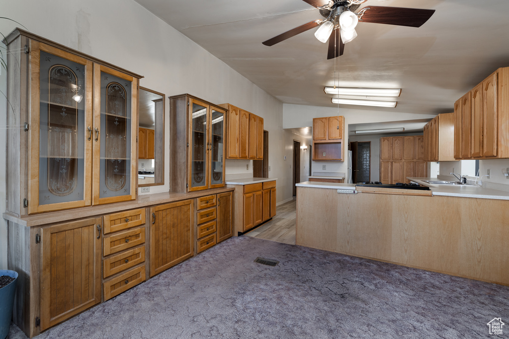 Kitchen with vaulted ceiling, carpet, kitchen peninsula, sink, and ceiling fan