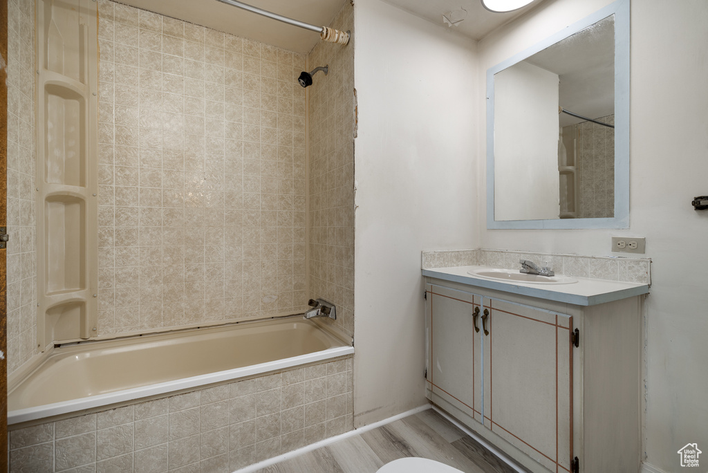 Bathroom with tiled shower / bath combo, vanity, and wood-type flooring