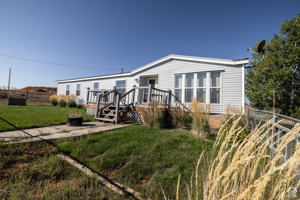 Manufactured / mobile home featuring a front lawn and a wooden deck