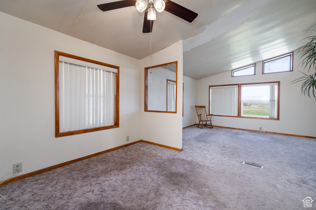Carpeted empty room with ceiling fan and vaulted ceiling