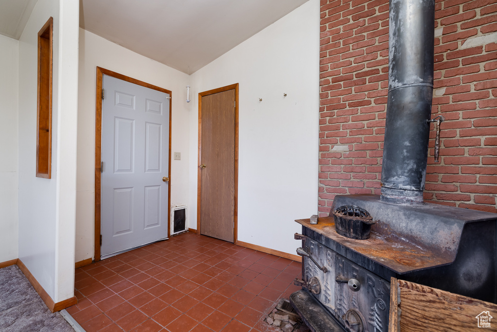 Entrance foyer featuring lofted ceiling, a wood stove, and dark tile patterned flooring