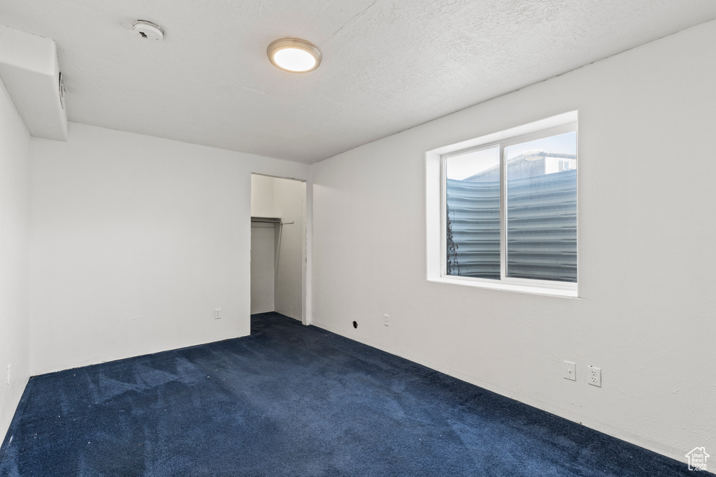 Spare room featuring dark colored carpet and a textured ceiling