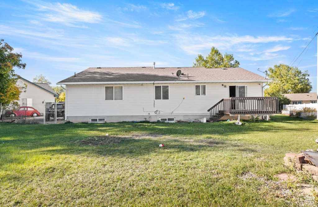Back of property with a wooden deck and a lawn