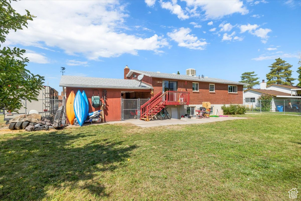 Back of house with cooling unit, a lawn, and a patio area