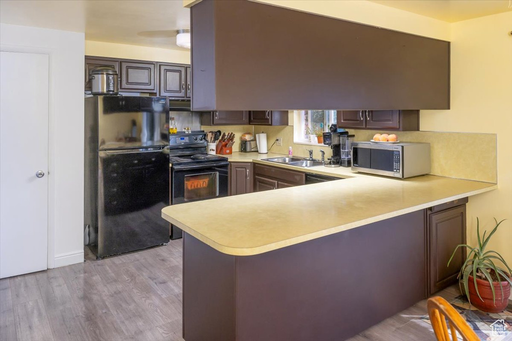 Kitchen with light hardwood / wood-style floors, sink, black appliances, kitchen peninsula, and ceiling fan