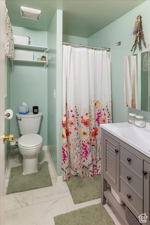 Bathroom featuring vanity, toilet, and curtained shower