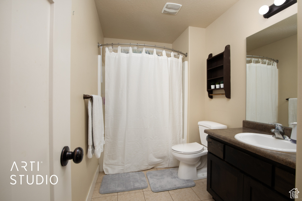 Bathroom with tile patterned flooring, toilet, a shower with curtain, vanity, and a textured ceiling