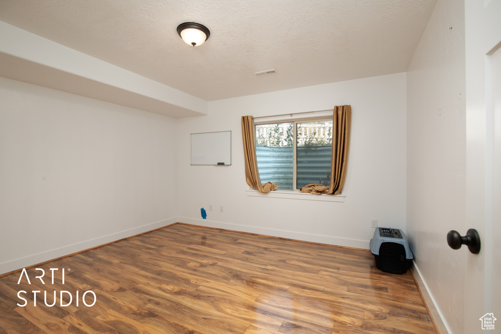 Spare room featuring a textured ceiling and wood-type flooring