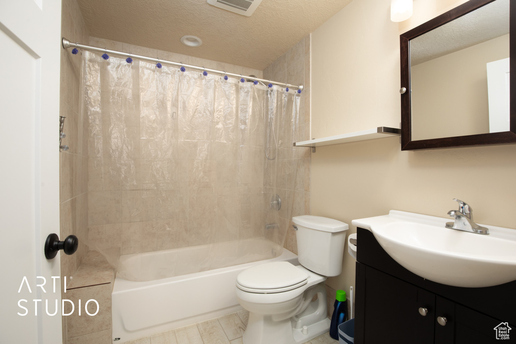 Full bathroom with shower / bathtub combination with curtain, toilet, a textured ceiling, and vanity