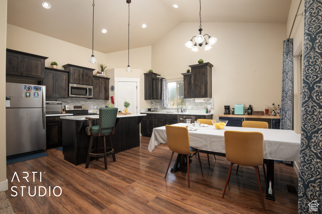 Dining room with dark hardwood / wood-style flooring, high vaulted ceiling, sink, and a notable chandelier