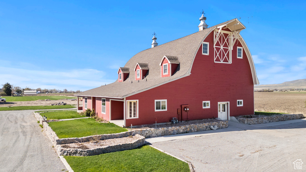 View of property exterior featuring a barn, an outdoor structure, a lawn, and brick siding