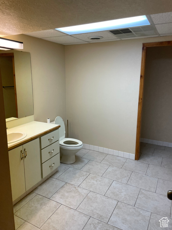 Bathroom featuring vanity, toilet, a paneled ceiling, and tile patterned floors