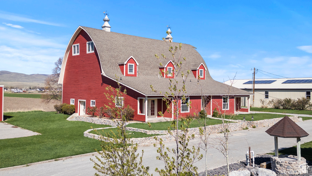 View of front facade with a front lawn, a barn, and a mountain view