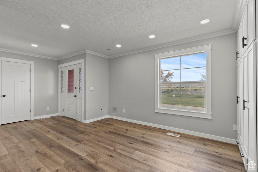 Unfurnished bedroom featuring crown molding, a textured ceiling, recessed lighting, light wood-type flooring, and baseboards