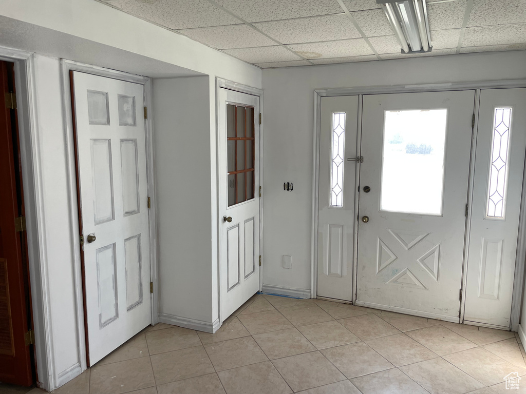 Foyer entrance featuring light tile patterned floors, a wealth of natural light, and a paneled ceiling