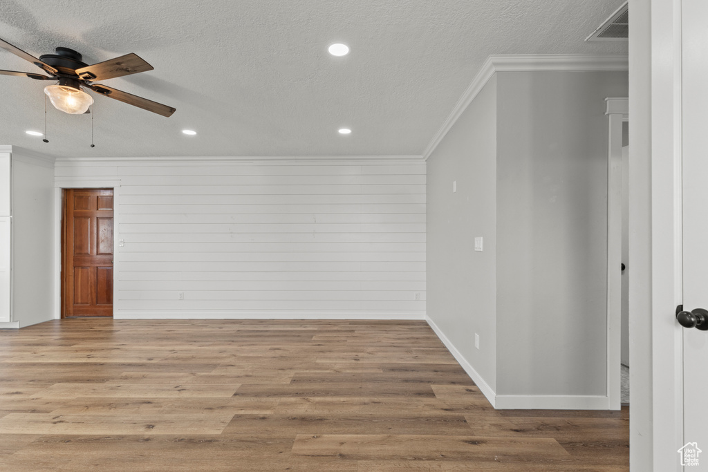 Empty room with crown molding, ceiling fan, baseboards, wood finished floors, and recessed lighting