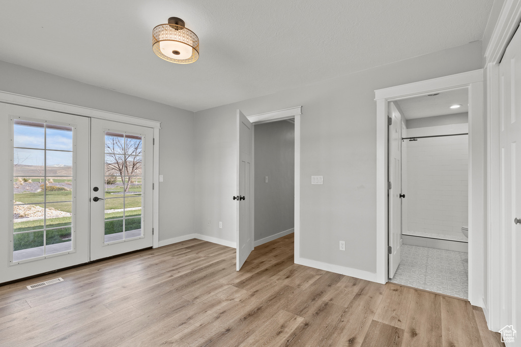 Unfurnished bedroom featuring french doors, access to outside, light wood-type flooring, and baseboards