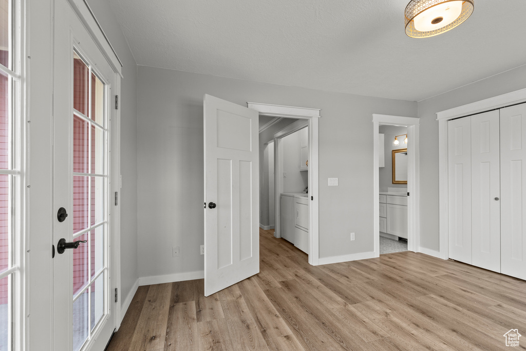 Unfurnished bedroom with light wood-style flooring, baseboards, washer / clothes dryer, and a closet
