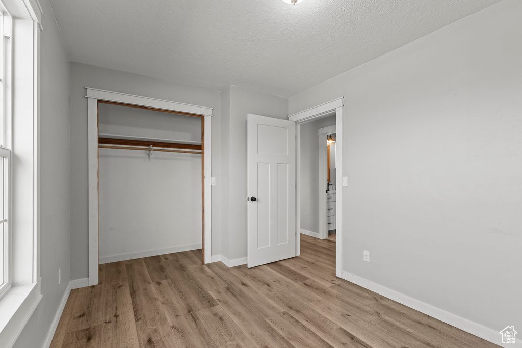 Unfurnished bedroom featuring light wood-style flooring, baseboards, and a closet