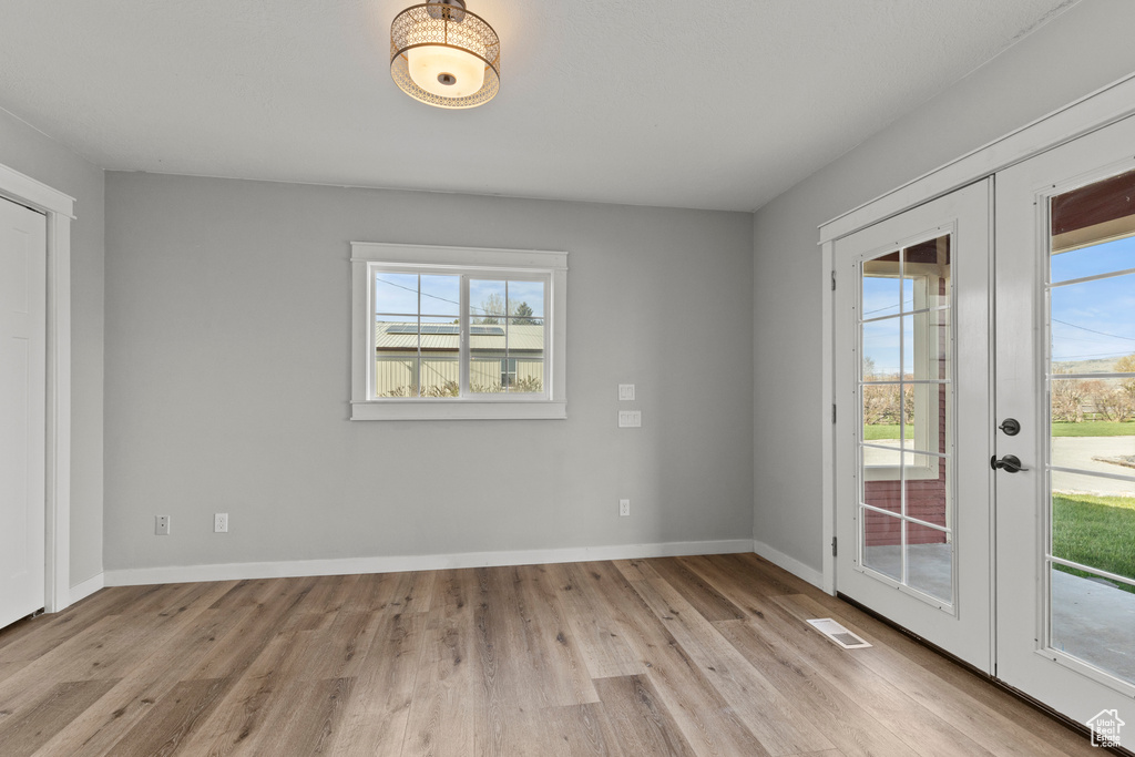 Empty room with french doors, wood finished floors, and baseboards