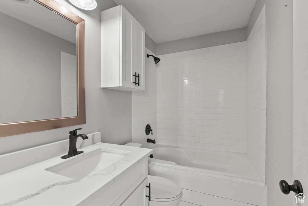 Bathroom with toilet, vanity, and  shower combination