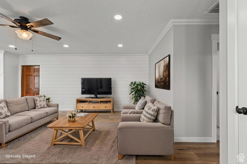 Living area with ornamental molding, wood finished floors, a ceiling fan, baseboards, and recessed lighting