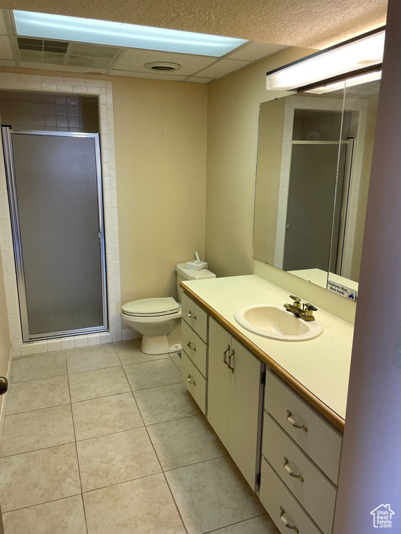 Bathroom with a shower with door, vanity, toilet, and tile patterned floors