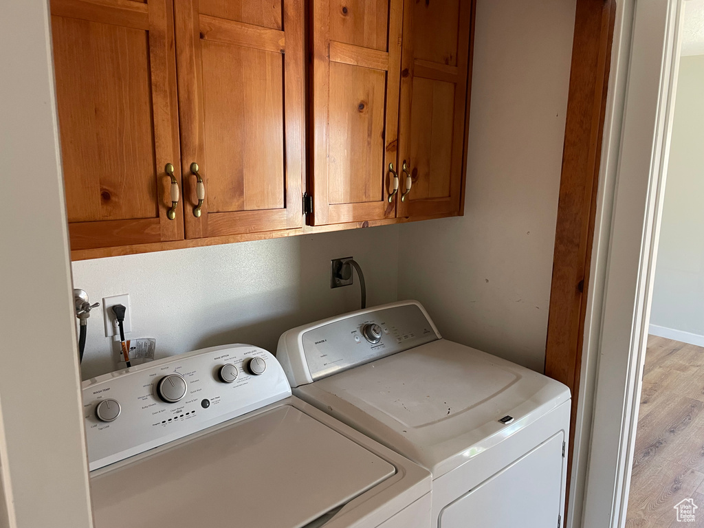 Laundry room featuring washer and dryer, cabinets, and light hardwood / wood-style flooring