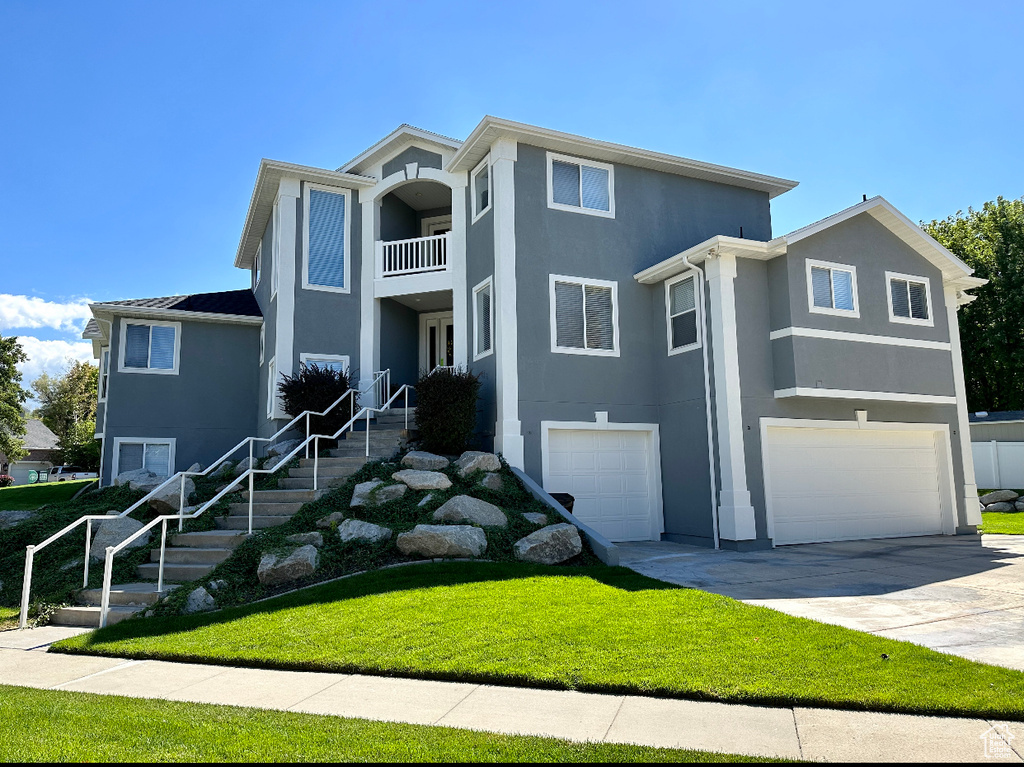 Front of property featuring a balcony, a garage, and a front lawn