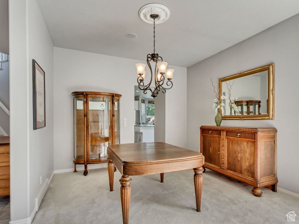 Dining area with light colored carpet and a notable chandelier