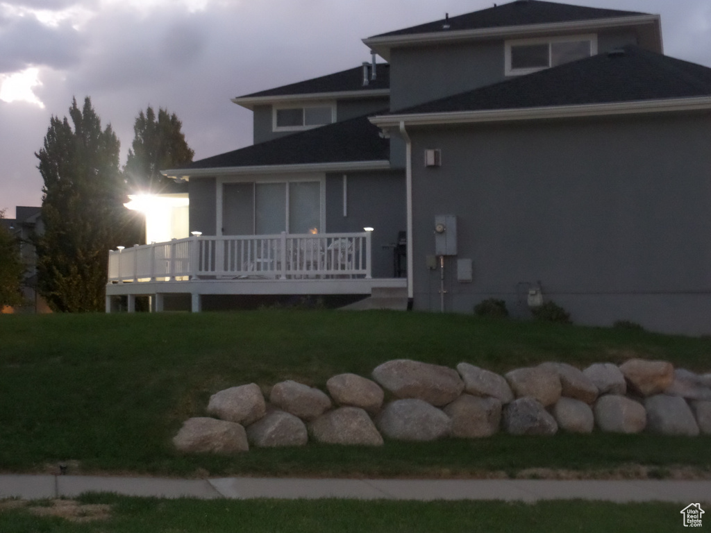 Back house at dusk with a deck and a yard