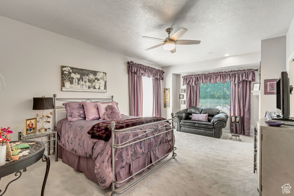 Carpeted bedroom with ceiling fan and a textured ceiling