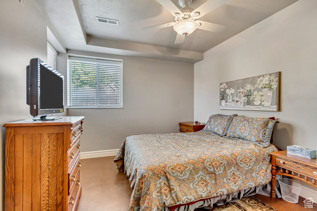 Carpeted bedroom with ceiling fan and a textured ceiling