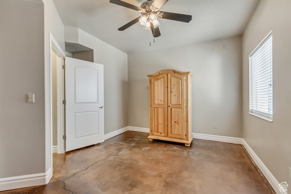 Unfurnished bedroom with ceiling fan and concrete floors