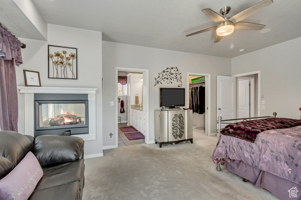 Bedroom featuring a spacious closet, ceiling fan, a closet, ensuite bath, and light colored carpet