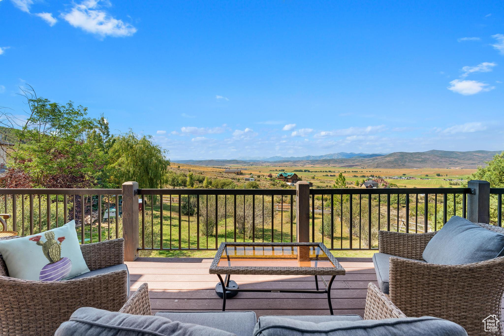 Wooden terrace featuring a mountain view, an outdoor hangout area, and a rural view