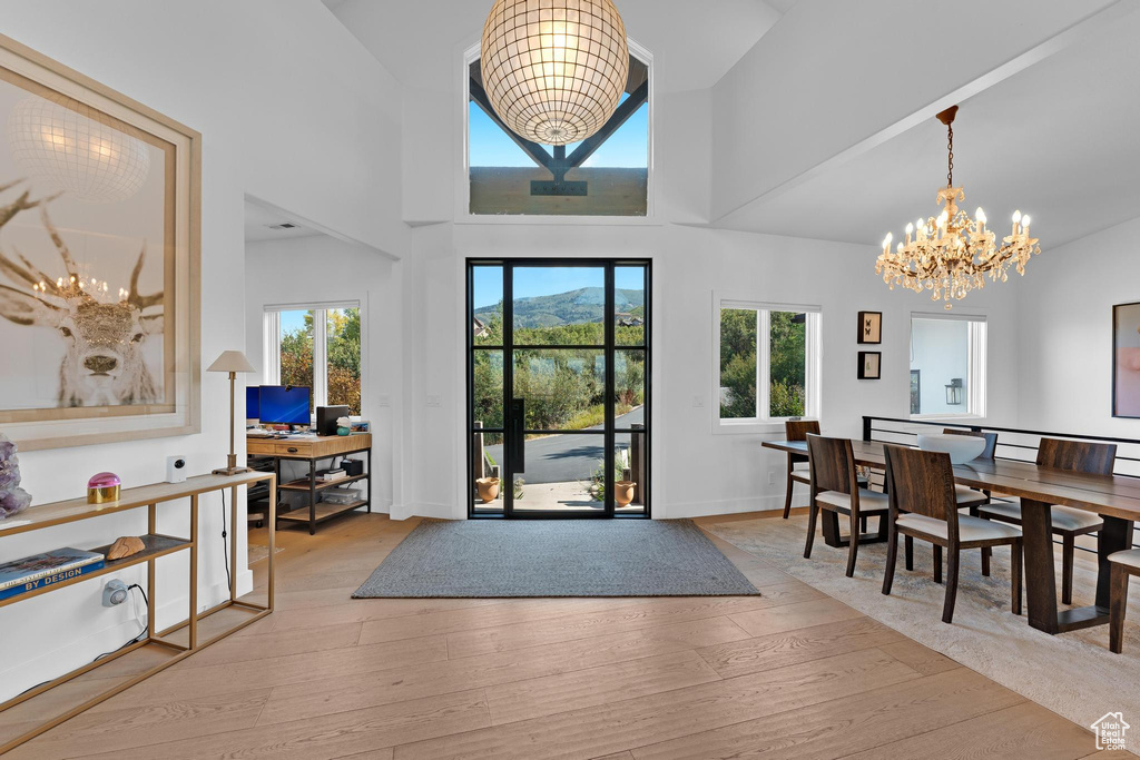 Interior space featuring light wood-type flooring, an inviting chandelier, and a towering ceiling