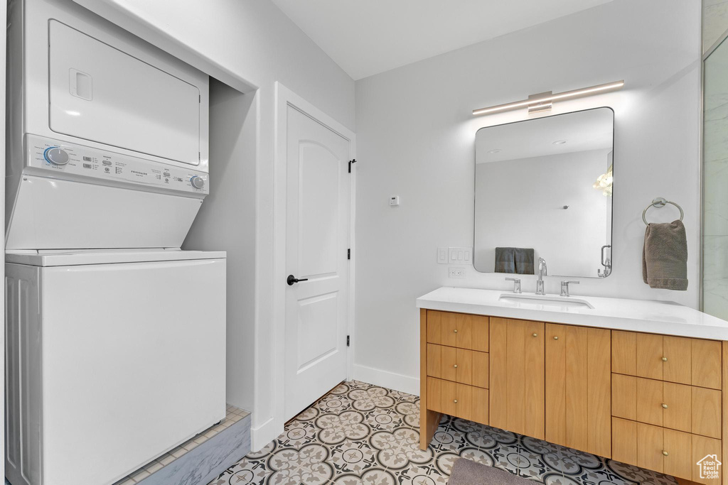 Bathroom with stacked washer / dryer, vanity, and tile patterned flooring