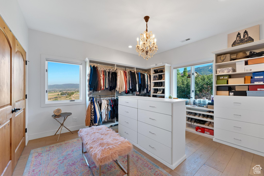 Walk in closet featuring a chandelier and light hardwood / wood-style floors