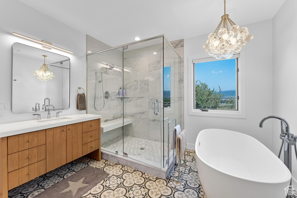 Bathroom with tile patterned flooring, shower with separate bathtub, an inviting chandelier, and vanity