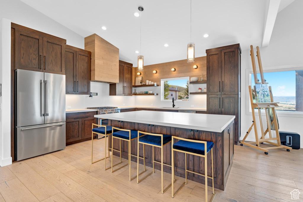 Kitchen featuring high end appliances, a wealth of natural light, a center island, and light wood-type flooring