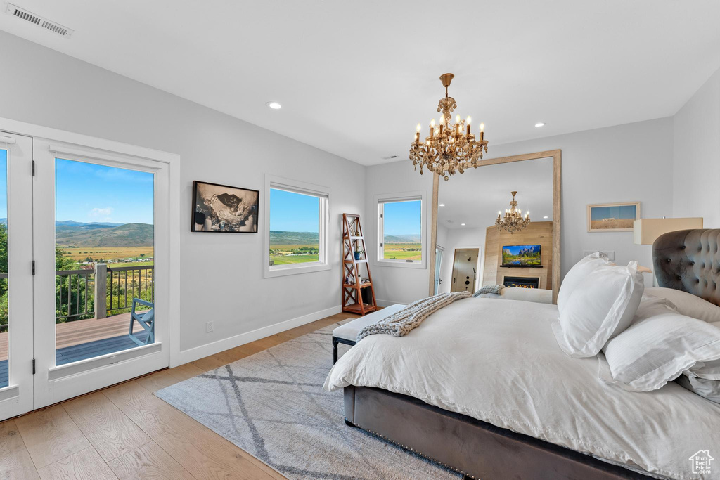 Bedroom with a notable chandelier, light wood-type flooring, and access to outside