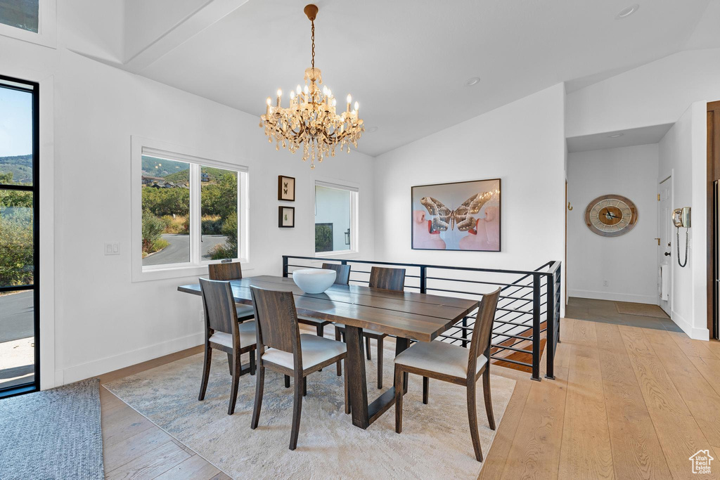 Dining area with vaulted ceiling, light hardwood / wood-style flooring, and a notable chandelier