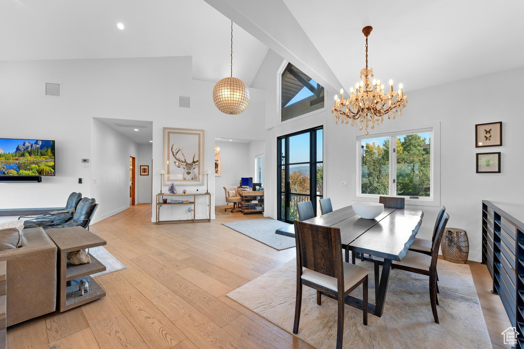 Dining area with high vaulted ceiling, a chandelier, and light hardwood / wood-style floors