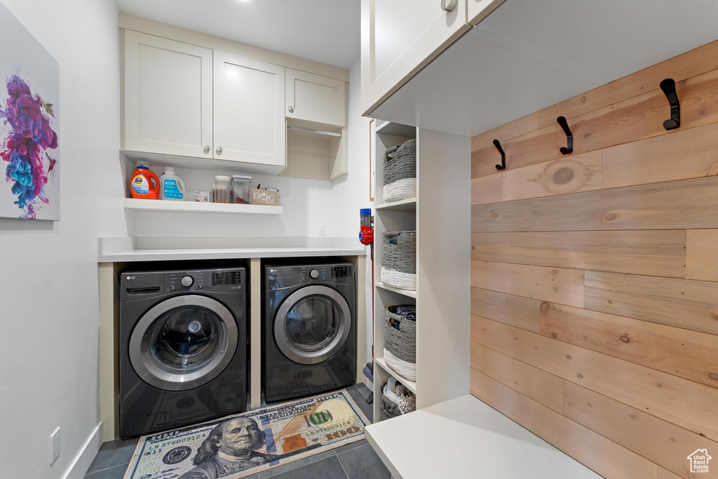 Clothes washing area featuring cabinets, washer and clothes dryer, and tile patterned floors