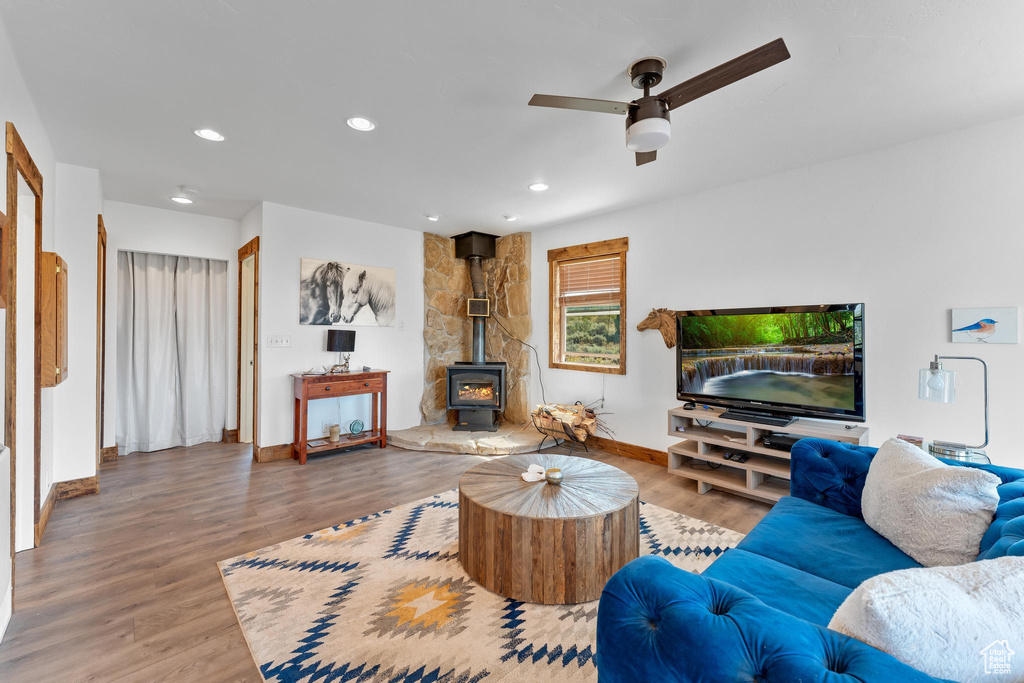 Living room featuring light hardwood / wood-style flooring, ceiling fan, and a wood stove