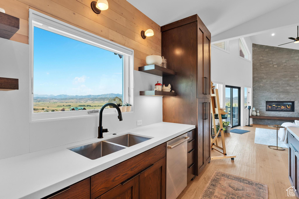 Kitchen with a mountain view, light hardwood / wood-style floors, a large fireplace, stainless steel dishwasher, and sink